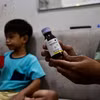 Một phụ huynh cầm chai thuốc ho con trai anh sử dụng dẫn đến tổn thương thận cấp tính tại Jakarta, Indonesia, ngày 11/2/2023. (Ảnh: AFP/TTXVN)