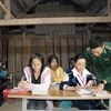 Trung úy Vì Văn Liêm, cán bộ Đồn biên phòng Mường Lạn, hướng dẫn cho các học viên tại lớp học xóa mù. (Ảnh: Hữu Quyết/TTXVN)