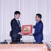 Phó Chủ tịch Ủy ban Nhân dân Thành phố Hồ Chí Minh Bùi Xuân Cường (phải) trao quà đối ngoại cho Thứ trưởng Bộ Ngoại giao Nhật Bản Komura Masahiro. (Ảnh: Xuân Khu/TTXVN)