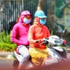 Để tránh sốc nhiệt, người ra đường luôn mặc áo chống nắng. (Ảnh: Tuấn Đức/TTXVN)