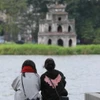 Đôi bạn trải nghiệm gió mùa Đông Bắc bên hồ Hoàn Kiếm. (Ảnh: Hoàng Hiếu/TTXVN)