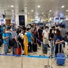 Hành khách xếp hàng chờ vào làm thủ tục khu vực an ninh soi chiếu. (Ảnh: PV/Vietnam+)