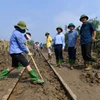 Nhân viên đường sắt dọn dẹp bùn trong khu vực ray tàu hỏa để thông tuyến, chạy tàu trở lại. (Ảnh: PV/Vietnam+)