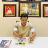 Khưu Tấn Bửu bên tác phẩm tranh gạo. (Ảnh: Ánh Tuyết/TTXVN)