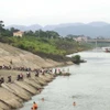 Người dân dựng xe la liệt bên bờ sông Đà để xuống tắm sông, phớt lờ cảnh báo nguy hiểm. (Ảnh: Trọng Đạt/TTXVN)