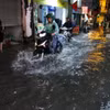 Người dân di chuyển khó khăn khi đi qua đoạn ngập. (Ảnh: Tuấn Anh/TTXVN)