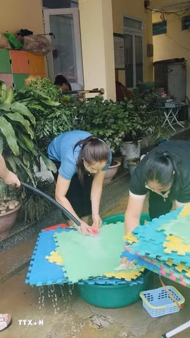 Giáo viên Trường Mầm non và Tiểu học Minh Long khẩn trương khắc phục hậu quả mưa lũ. (Ảnh: TTXVN phát)