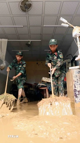 Lực lượng quân đội hỗ trợ người dân tổ 4, xã Sông Mã, Sơn La, thu gom bùn đất, cành cây, rác bị tràn về trong đợt lũ vừa qua. (Ảnh: Quang Quyết/TTXVN)