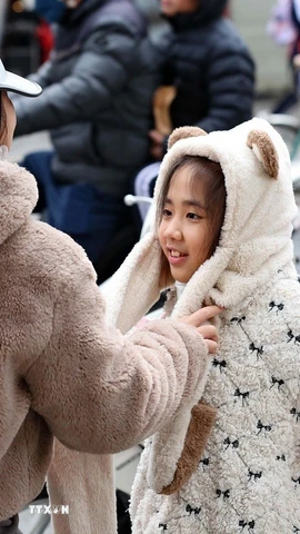 Trẻ em được giữ ấm khi lưu thông bằng xe máy trong những ngày rét đậm. (Ảnh: Vũ Quang/TTXVN)