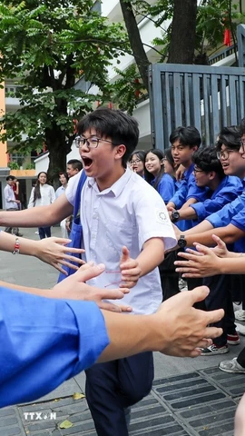 Các bạn sinh viên tình nguyện chia sẻ niềm vui và khích lệ tinh thần thí sinh tại điểm trường THCS Ngô Sĩ Liên (quận Hai Bà Trưng). (Ảnh: Khánh Hòa/TTXVN_