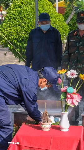 Lực lượng chuyên môn tiến hành đưa hài cốt liệt sỹ ra khỏi mộ để lấy mẫu giám định. (Ảnh: Thanh Liêm/TTXVN)
