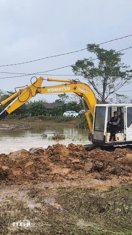 Xe múc được huy động khắc phục đoạn đê bị sạt lở do mưa lũ kéo dài. (Ảnh: Mai Trang/TTXVN)