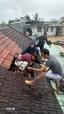 Lũ dâng cao, người dân phải phá mái nhà leo lên để tránh nguy hiểm ở Gia Lai. (Ảnh: TTXVN phát)