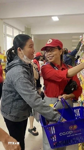 Nhân viên Hội Chữ thập Đỏ Đà Nẵng hỗ trợ người dân lựa chọn các nhu yếu phẩm tại Chương trình Tết Nhân ái. (Ảnh: Trần Lê Lâm/TTXVN)