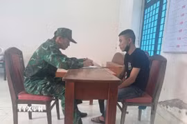 Cán bộ nghiệp vụ thuộc Đồn Biên phòng Cửa khẩu quốc tế Mộc Bài làm việc với đối tượng Phạm Minh Hải. (Ảnh: TTXVN phát)