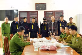Đối tượng Phạm Lê Tuấn Anh (áo khoác đen) và Đinh Hồng Thuấn (áo dài xám) cùng tang vật bị thu giữ. (Nguồn: Công an cung cấp)
