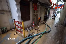 Công nhân Công ty vệ sinh môi trường đô thị Hà Nội và người dân đang khẩn trương làm sạch ngõ số 7 Giang Văn Minh để đưa cuộc sống sinh hoạt lại bình thường. (Ảnh: An Đăng/TTXVN)