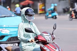 Mỗi khi phải ra đường, dù người lớn hay trẻ em đều dùng mọi biện pháp như khẩu trang hay áo chống nắng để chống lại cái nắng nóng gay gắt. (Ảnh: Minh Đức/TTXVN)