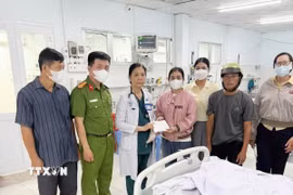Đại diện Đảng ủy, Ủy ban Nhân dân thị trấn Vĩnh Thạnh Trung, Công an thị trấn Vĩnh Thạnh Trung trao tiền hỗ trợ cho gia đình cháu L., nạn nhân bị hành hung, bước đầu lo chi phí điều trị tại bệnh viện. (Ảnh: Công Mạo/TTXVN)