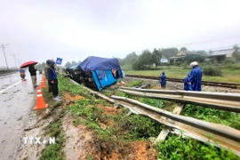 Xe khách lưu thông hướng Bắc-Nam đã húc vào 30m hộ lan trên Quốc lộ 1A rồi lật nghiêng nằm cạnh hành lang đường sắt. (Ảnh: Nguyên Linh/TTXVN)