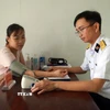 Bác sĩ tại Bệnh xá quân y đảo Sinh Tồn thăm khám cho người dân trên đảo. (Ảnh: Hữu Quyết/TTXVN)