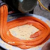 Xôi gấc làm bánh giầy được xay nhuyễn, có màu cam đỏ. (Ảnh: Thanh Hải/TTXVN)
