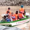Giáo viên, học sinh được lực lượng chức năng đưa qua sông bằng thuyền. (Ảnh: TTXVN phát)