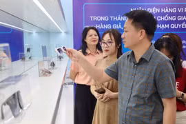 Lãnh đạo Cục Quản lý và Phát triển thị trường trong nước hướng dẫn nhận biết hàng không chính hãng. (Ảnh: PV/Vietnam+)