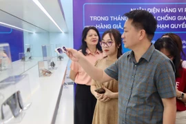 Lãnh đạo Cục Quản lý và Phát triển thị trường trong nước hướng dẫn nhận biết hàng không chính hãng. (Ảnh: PV/Vietnam+)