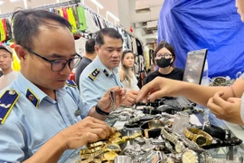 Cán bộ Cục Quản lý và Phát triển thị trường trong nước trực tiếp kiểm tra những "điểm nóng" về buôn lậu, hàng giả. (Ảnh: PV/Vietnam+)