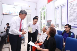Chủ tịch Ủy ban Nhân dân phường Hồng Hà trao đổi với người dân đến làm thủ tục hành chính tại Điểm số 1-Khu vực Tứ Liên. (Ảnh: Xuân Quảng/Vietnam+)