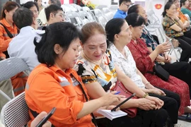 Nhân viên EVNHANOI hướng dẫn khách hàng sử dụng App để theo dõi lượng điện tiêu thụ. (Ảnh: evnhanoi)