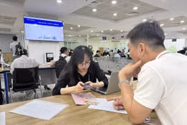 Cán bộ Trung tâm phục vụ hành chính công hướng dẫn người dân lấy số thứ tự online đối với hồ sơ liên quan đến đất đai qua ứng dụng iHanoi. (Ảnh: Quốc Lũy/TTXVN)