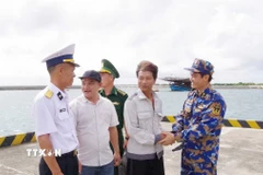 Ngư dân Tiêu Viết Bút (thứ 2 bên phải sang) bắt tay tạm biệt cán bộ, chiến sỹ trên đảo Trường Sa trước khi trở lại tàu cá. (Ảnh: TTXVN phát)