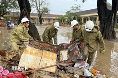 Lực lượng Quân đội hỗ trợ người dân thu dọn rác và bùn đất sau khi nước rút. (Ảnh: Nguyên Dung/TTXVN)