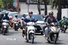 Người dân mặc đồ bảo hộ chống nắng nóng khi tham gia giao thông trên đường Hùng Vương, phường Thuận Hóa, thành phố Huế. (Ảnh: Nguyên Lý/TTXVN)
