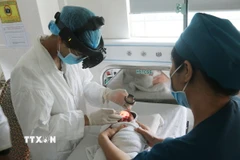 Bé trai M.K.C (78 ngày tuổi, ngụ xã Phú Vinh, tỉnh Đồng Nai) được các bác sỹ kiểm tra biến chứng về thị lực. (Ảnh: Lê Xuân/TTXVN)