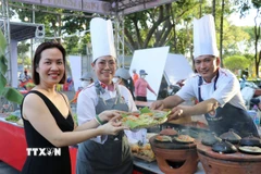 Du khách thích thú trải nghiệm món "bánh xèo ngàn năm" được làm bởi các đầu bếp chuyên nghiệp đến từ Thành phố Hồ Chí Minh. (Ảnh: Nguyễn Thành/TTXVN)