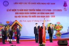 Đồng chí Bùi Thị Minh Hoài, Ủy viên Bộ Chính trị, Bí thư Trung ương Đảng, Bí thư Đảng ủy Mặt trận Tổ quốc, các đoàn thể Trung ương, Chủ tịch Ủy ban Trung ương Mặt trận Tổ quốc Việt Nam gắn Huân chương Lao động hạng Nhất lên lá cờ truyền thống. (Ảnh: An Đăng/ TTXVN)