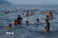 Du khách thích thú vui chơi, tắm biển dưới làn nước trong xanh của biển Cửa Lò. (Ảnh: Bích Huệ/TTXVN)