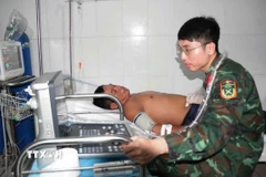 Bác sỹ quân y tiến hành siêu âm ổ bụng cho ngư dân Trần Công Nhanh. (Ảnh: TTXVN phát)