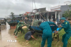 Các lực lượng hỗ trợ giúp đỡ người dân chằng chống, bảo vệ phương tiện trước khi bão vào đất liền. (Ảnh: Đoàn Hữu Trung/TTXVN)
