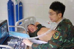 Bác sỹ Trung tâm y tế thị trấn Trường Sa siêu âm ổ bụng cho bệnh nhân Võ Sỹ Danh. (Ảnh: TTXVN phát)