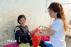 Nhân viên Trung tâm Y tế Tu Mơ Rông trao phần quà gồm những vật dụng thiết yếu của mẹ và bé cho các sản phụ. (Ảnh: TTXVN phát)