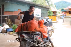 Người dân bản Piêng Pèn (xã Mỹ Lý, tỉnh Nghệ An) ra bản Yên Hòa nhận hàng hỗ trợ được vận chuyển bằng đường sông Nậm Nơn, rồi tiếp tục chở về bản bằng xe máy. (Ảnh: Xuân Tiến/TTXVN)