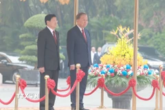 Tổng Bí thư Tô Lâm và Tổng Bí thư, Chủ tịch nước Lào Thongloun Sisoulith trên bục danh dự, thực hiện nghi thức chào cờ. (Ảnh: Thống Nhất/TTXVN)