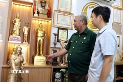 Cựu chiến binh Phan Trọng Điền (trái) giới thiệu sản phẩm đúc đồng của công ty. (Ảnh: Nguyễn Lành/TTXVN)