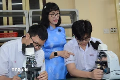 Cô Nguyễn Thị Diệu Hạnh hướng dẫn đội tuyển học sinh giỏi sinh thực hành. (Ảnh: Văn Dũng/TTXVN)
