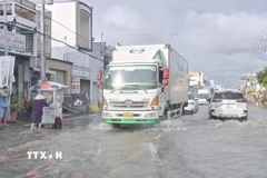 Các phương tiện giao thông di chuyển chậm trên tuyến đường ngập sâu. (Ảnh: Chanh Đa/TTXVN)