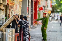 Lực lượng chức năng đi vận động hộ kinh doanh không lấn chiếm vỉa hè tại phố Phan Chu Trinh, phường Cửa Nam. (Ảnh: Quốc Lũy/TTXVN)